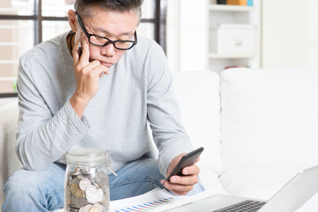 Man using cell phone with money nearby.